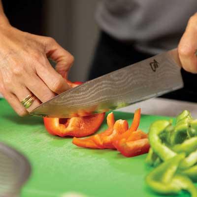 close up of chef using knife to cut peppers 